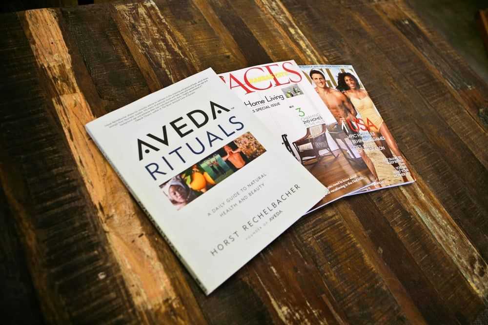 A wooden table displaying three magazines with various covers and articles.